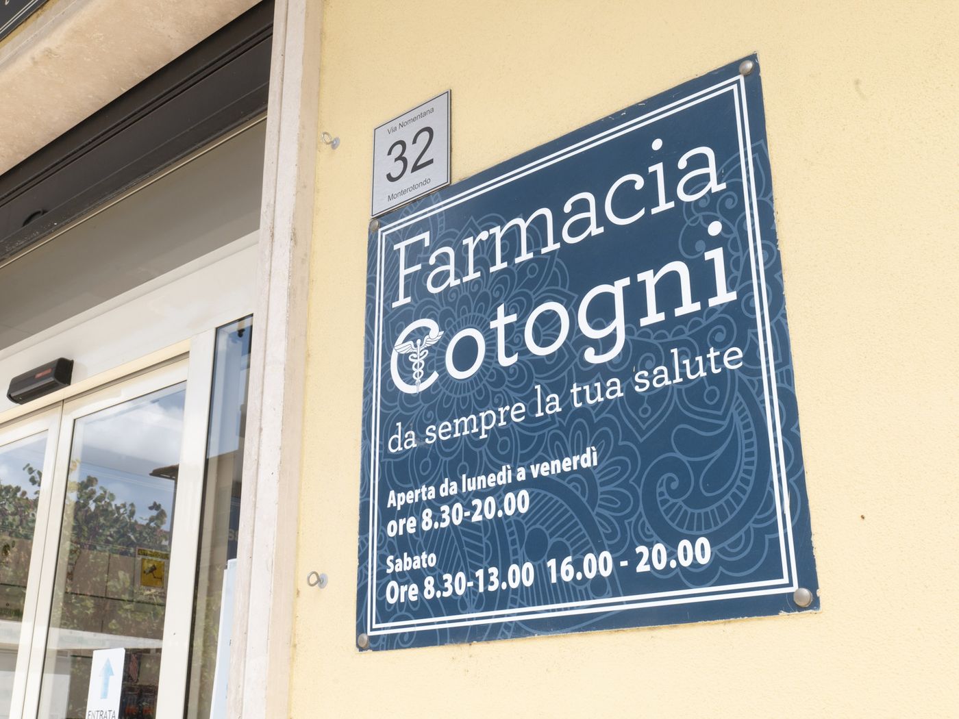 La targa della Farmacia Cotogni all’ingresso di Via Nomentana 32, con gli orari di apertura